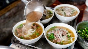 A bowl of Vietnamese pho with herbs, lime and chili